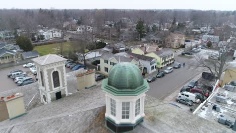 A-drone-captures-an-aerial-view-of-Niagara-on-the-Lake's-downtown-courthouse,-passing-over-the-tower-on-the-roof,-capturing-the-surrounding-historical-buildings