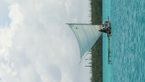 Sailing-in-Upi-Bay,-New-Caledonia-on-a-traditional-pirogue-sailboat---vertical