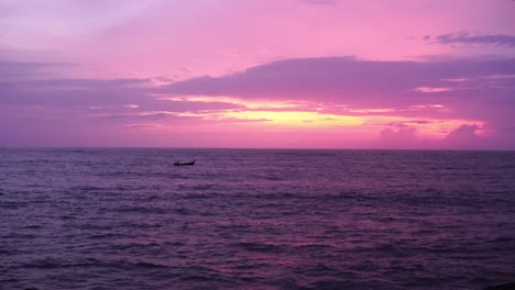 Panoramablick-Auf-Ein-Fischerboot-Mit-Langem-Schwanz,-Das-Nach-Sonnenuntergang-Am-Meer-Vorbeifährt,-Mit-Wunderschönem-Rosa-Und-Rötlichen-Himmel-Im-Meer