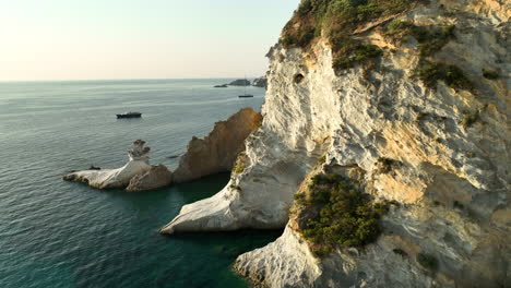 Slow-drone-dolly-shot-of-steep-cliff-walls-illuminated-by-the-warm-rising-morning-sun-at-Isola-di-Ponza