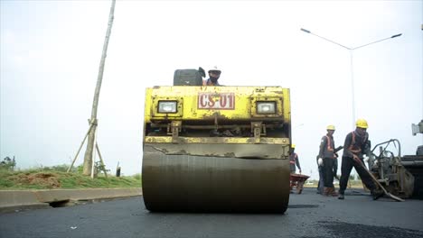 Process-of-asphalting-road-construction-infrastructure-by-compressing,-compacting,-leveling-and-smoothing-the-asphalt-road-surface-using-a-tandem-roller