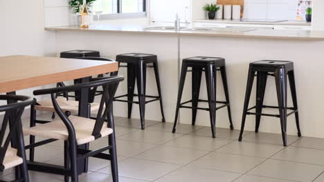 Stone-bench-top-kitchen-with-bar-stools-with-adjacent-dinging-table