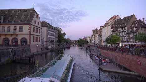 Youth-Enjoys-Lovely-Evening-near-by-the-Ill-River-in-Strasbourg-with-Passing-Ferry