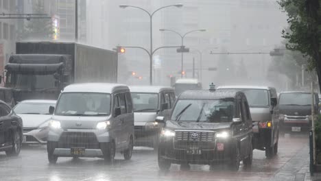 City-Centre-Road-Traffic-and-Commuters-during-heavy-Rain,-Kabukicho,-Shinjuku,-Tokyo,-Japan