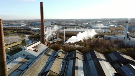Pilkington-glass-factory-warehouse-buildings-aerial-view-orbits-industrial-rooftop-smokestack-skyline