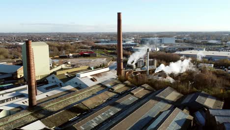 Pilkington-glass-factory-warehouse-buildings-aerial-view-pan-across-smokestack-rooftop