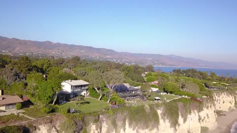 4K-Aerial-Footage-of-Mansions-in-Malibu,-California-with-the-Malibu-Pier-and-Santa-Monica-Mountains-in-the-Background-on-a-Sunny-Day