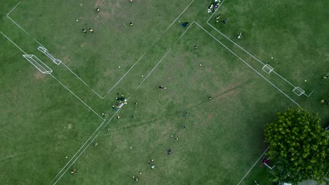 Luftaufnahme-Von-Oben-Nach-Unten-Von-Männern,-Die-Fußball-Auf-Einem-Rasenfußballplatz-Trainieren