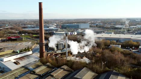 Pilkington-glass-factory-warehouse-buildings-aerial-view-zoom-in-towards-smoking-industrial-facility