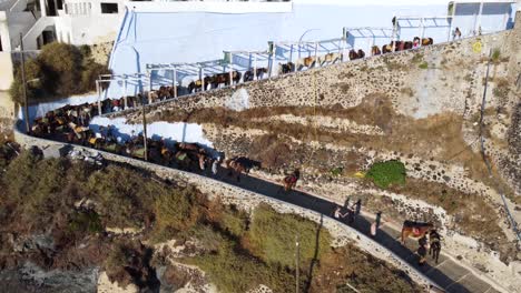 Tourists-climbing-Karavolades-Stairs-leading-from-a-hilltop-village-down-a-steep-hill-to-a-harbor-of-Santorini-island