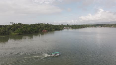 Boat-with-tourists-on-dulce-river-near-castillo-de-san-felipe,-aerial