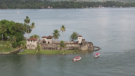 Boats-cruising-near-Castillo-de-San-Felipe-de-Lara-at-Rio-dulce,-aerial
