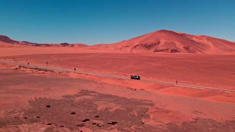 Aerial-view-of-a-car-driving-on-a-road-in-middle-of-dunes-in-Coquimbo,-Chile