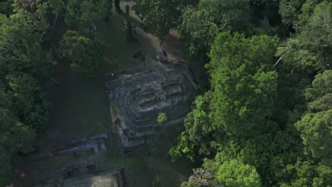 Peten-jungle-with-old-mayan-ruins-at-Yaxha-Guatemala-between-trees,-aerial