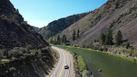 Car-driving-on-two-lane-road-next-to-snake-river-in-Idaho-Rocky-Mountains