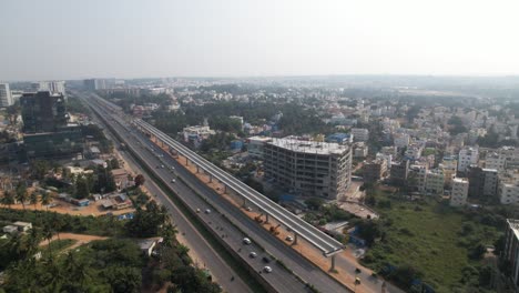 An-aerial-video-shows-a-service-road,-fast-moving-automobiles,-and-residential-and-commercial-buildings-on-an-Indian-highway-that-is-expanding-quickly