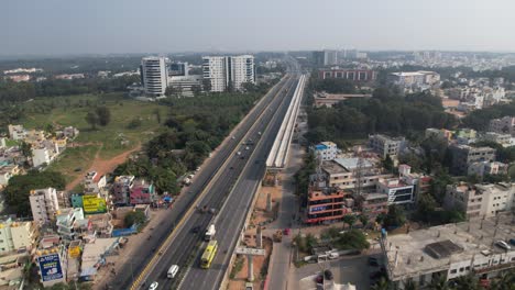 Aerial-video-of-a-rapidly-growing-Indian-highway-featuring-a-service-road,-fast-moving-cars,-and-residential-and-commercial-structures