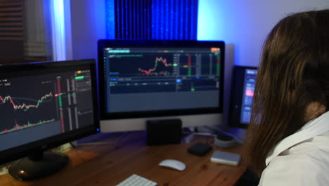 Female-stock-trader-wearing-headset-making-trades-on-the-market-looking-at-graphs-in-an-office