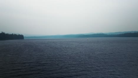 Luftwagen-über-Einem-Nebligen,-Kalten-See-Zum-Sonnenfisch-Segelboot-Auf-Windgepeitschtem-Wasser