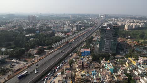 Dramatic-aerial-footage-shows-residential-and-commercial-buildings-on-an-expanding-Indian-highway,-along-with-a-service-road-and-rapidly-moving-cars