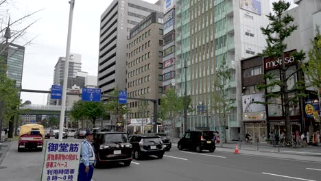 Verkehr-Gesehen-Entlang-Der-Midosuji-Avenue-Mit-Verkehrspolizist-In-Osaka,-Japan