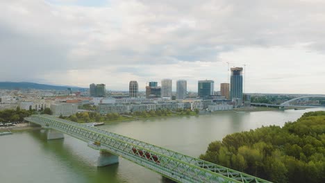Red-Tram-on-The-Old-Bridge-in-Down-Town-on-a-cloudy-day-in-Bratislava,-Slovakia---aerial-view