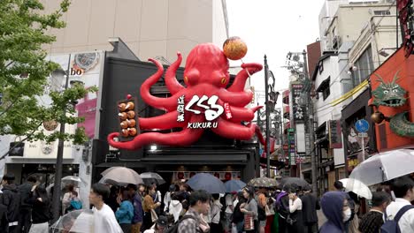 Gente-Haciendo-Cola-Fuera-De-Takoyaki-Kukuru-Dotonbori-En-Un-Día-Lluvioso-En-Osaka