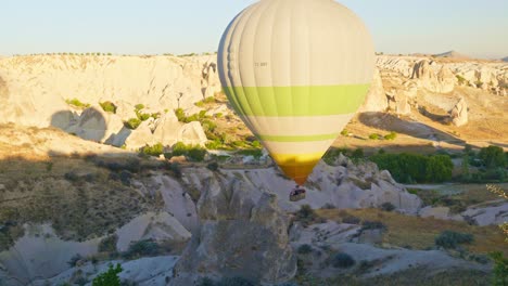 Hot-air-balloon-descends-slowly-love-valley-sunrise-tourists-adventure
