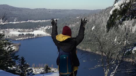 A-young-woman-celebrates-reaching-the-viewpoint-over-Longemer-Lake-in-the-Vosges-Mountains