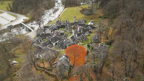 Retreating-drone-shot-over-the-stone-houses-of-the-village-of-Cavergno,-situated-in-the-district-of-Vallemaggia,-in-the-canton-of-Ticino-in-Switzerland