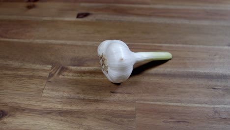 Whole-head-of-garlic-without-peeling-and-with-its-stem,-on-wooden-kitchen-table