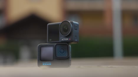 DJI-Osmo-Action-4-Camera-Stacked-On-Top-Of-GoPro-Hero-12-On-Table-With-Bokeh-Background