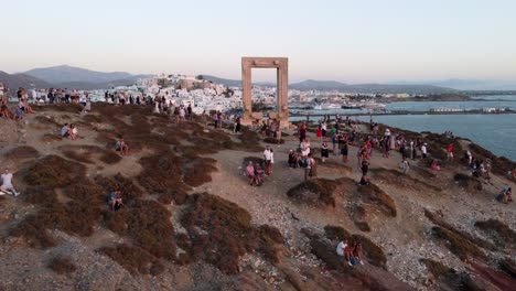 Turistas-Disfrutando-De-La-Puesta-De-Sol-En-El-Templo-De-Apolo-De-La-Isla-De-Naxos,-Grecia,-Vista-Aérea