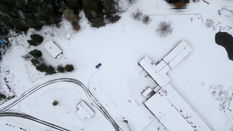 Drone-top-shot-rising-and-filming-some-buildings-and-an-empty-parking-lot-with-snow-on,-Sweden
