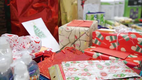Langsamer-4K-Rotschuss,-Stapel-Festlicher-Körperpflegeprodukte,-Bunte-Weihnachtsgeschenke,-Taschen,-Vorabendschachteln,-Grußkarten,-Verpackt-In-Mehrfarbigem-Weihnachtspapier,-Geheimer-Weihnachtsmann