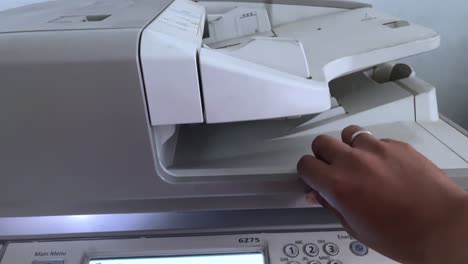 A-person's-hand-closes-the-photocopier-cover-to-photocopy-a-file