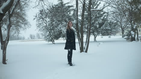 Happy-woman-outside-in-slow-motion,-Christmas-winter-snow-as-snowflakes-fall-in-cinematic-slow-motion
