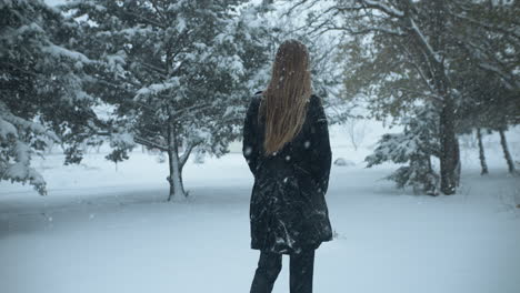 Woman-walking-outside-in-slow-motion,-Christmas-winter-snow-as-snowflakes-fall-in-cinematic-slow-motion