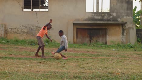 Botando-El-Balón-Sin-Zapatos-Pero-Muy-Feliz-De-Jugar-Con-Sus-Amigos-En-Un-Campo-De-Fútbol-Comunitario-En-Kumasi,-Ghana