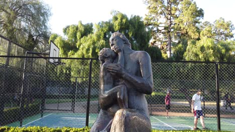 Statue-of-a-little-child-Kissing-his-Mother-made-in-Bronze-at-Argentinian-Plaza-Urban-Park-in-Flores-Neighborhood,-Buenos-Aires