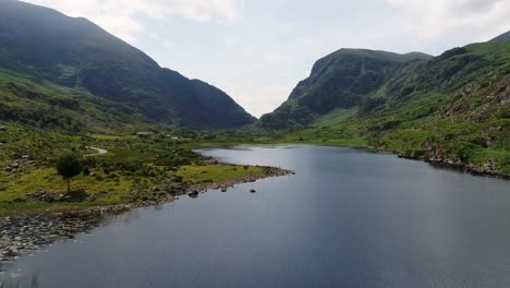 A-low-flying-drone-shot-over-a-lake-through-the-Gap-of-Dunloe-of-Killarney-National-Park-in-Ireland