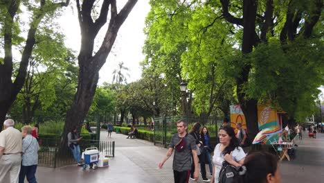 Buenos-Aires-Argentina-People-Walk-Around-Green-Urban-Park,-Flores-Neighborhood-Plaza-Pueyrredon