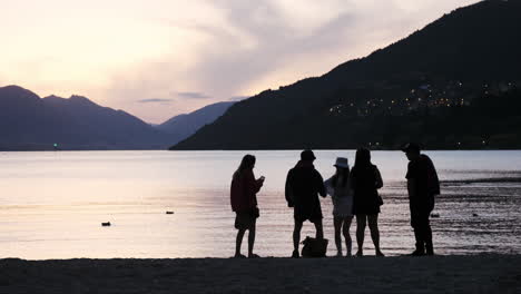 Young-adult-silhouettes-dancing-and-partying-in-Queenstown-on-the-beach-at-sunset