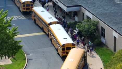 Students-running-towards-yellow-school-buses-after-high-school-dismissal-in-USA