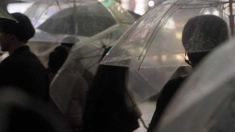 Tokyo-Pedestrian-Crowd-with-Umbrellas,-Shibuya-Crossing-at-Night,-Tokyo,-Japan