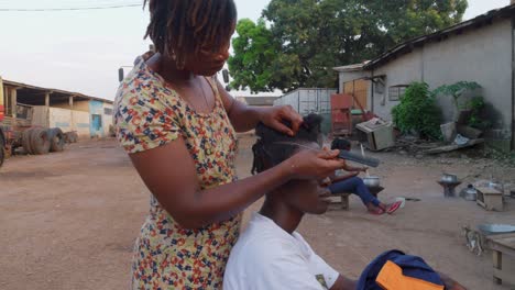 Woman-with-skillful-hands-carefully-braiding-the-braids-of-another-woman,-Kumasi,-Ghana