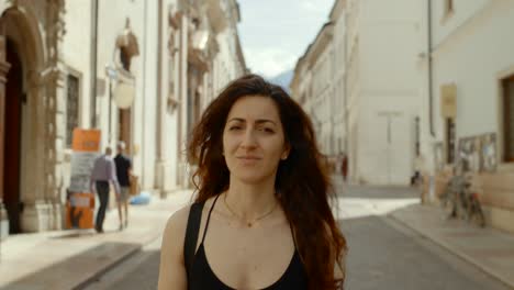 Carefree-Solo-Female-Traveller-Walking-Along-European-Street-Looking-Around