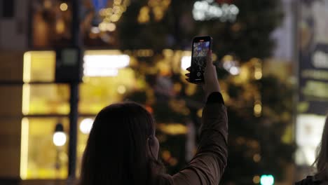 Mujer-Filmando-El-Cruce-De-Shibuya-Con-Un-Teléfono-Inteligente-Por-La-Noche,-Tokio,-Japón