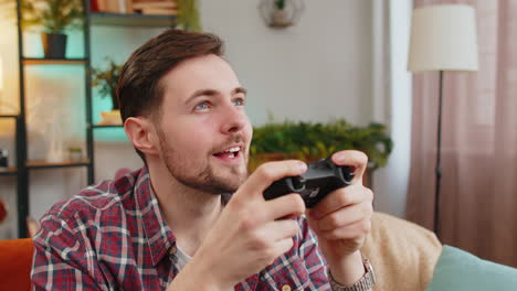 Man-using-joystick-controller-playing-video-console-television-game-fun-enjoying-at-home-room-sofa