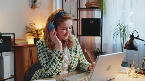 Businesswoman-listening-music-through-wireless-headphones-relaxing-taking-a-break,-laptop-on-table